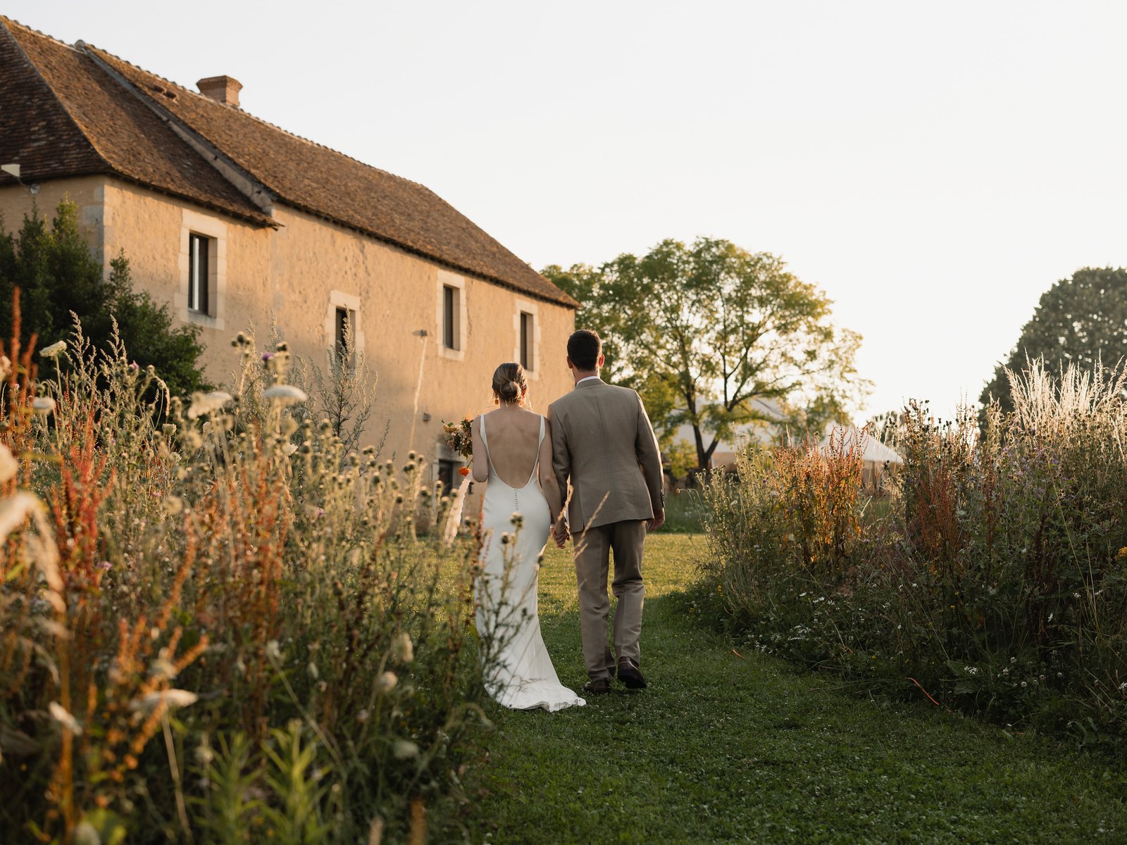 Les mariés s'éloignent vers la maison à travers la prairie fleurie