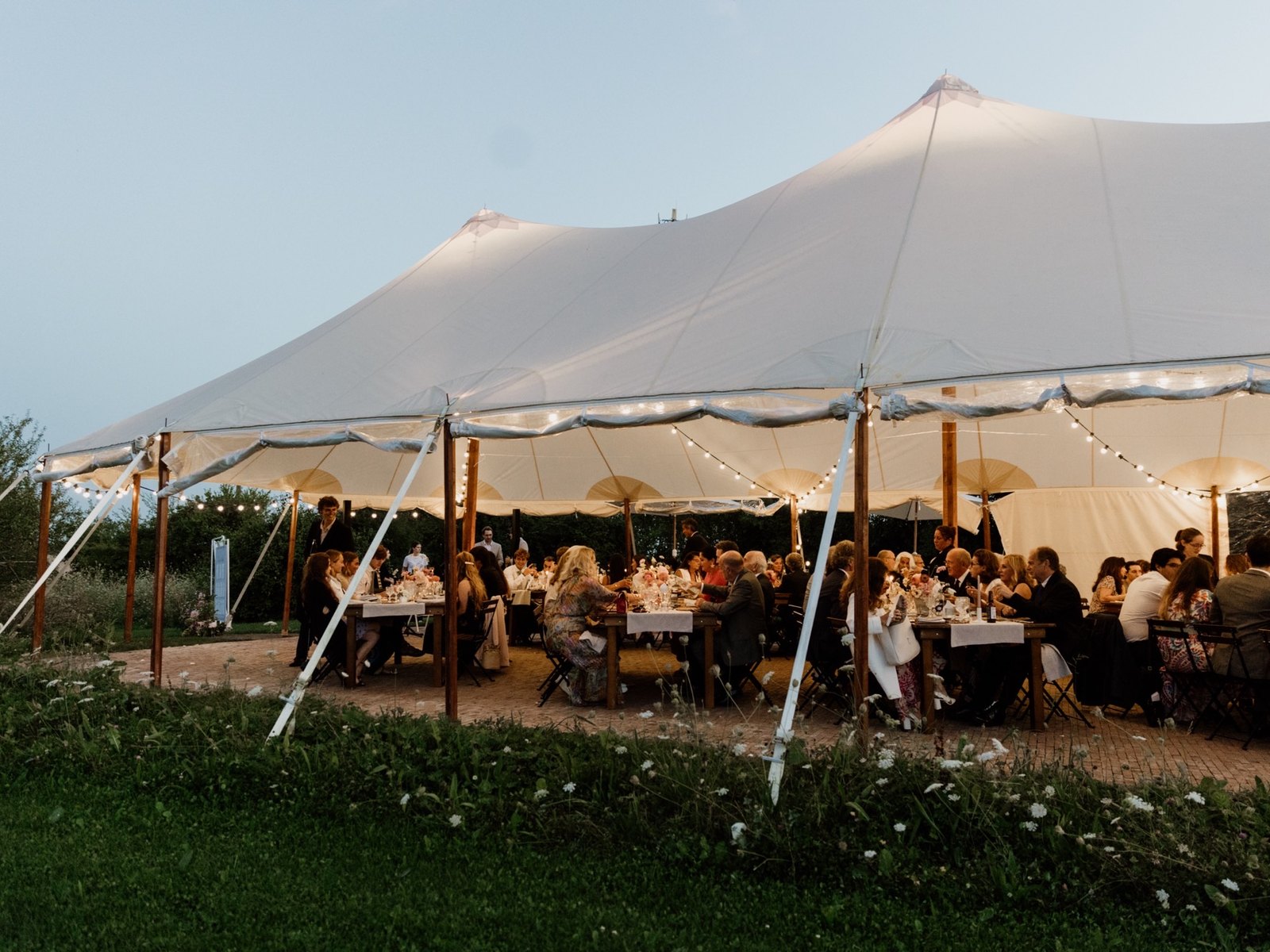 Dîner de mariage sous le chapiteau à la tombée du soir