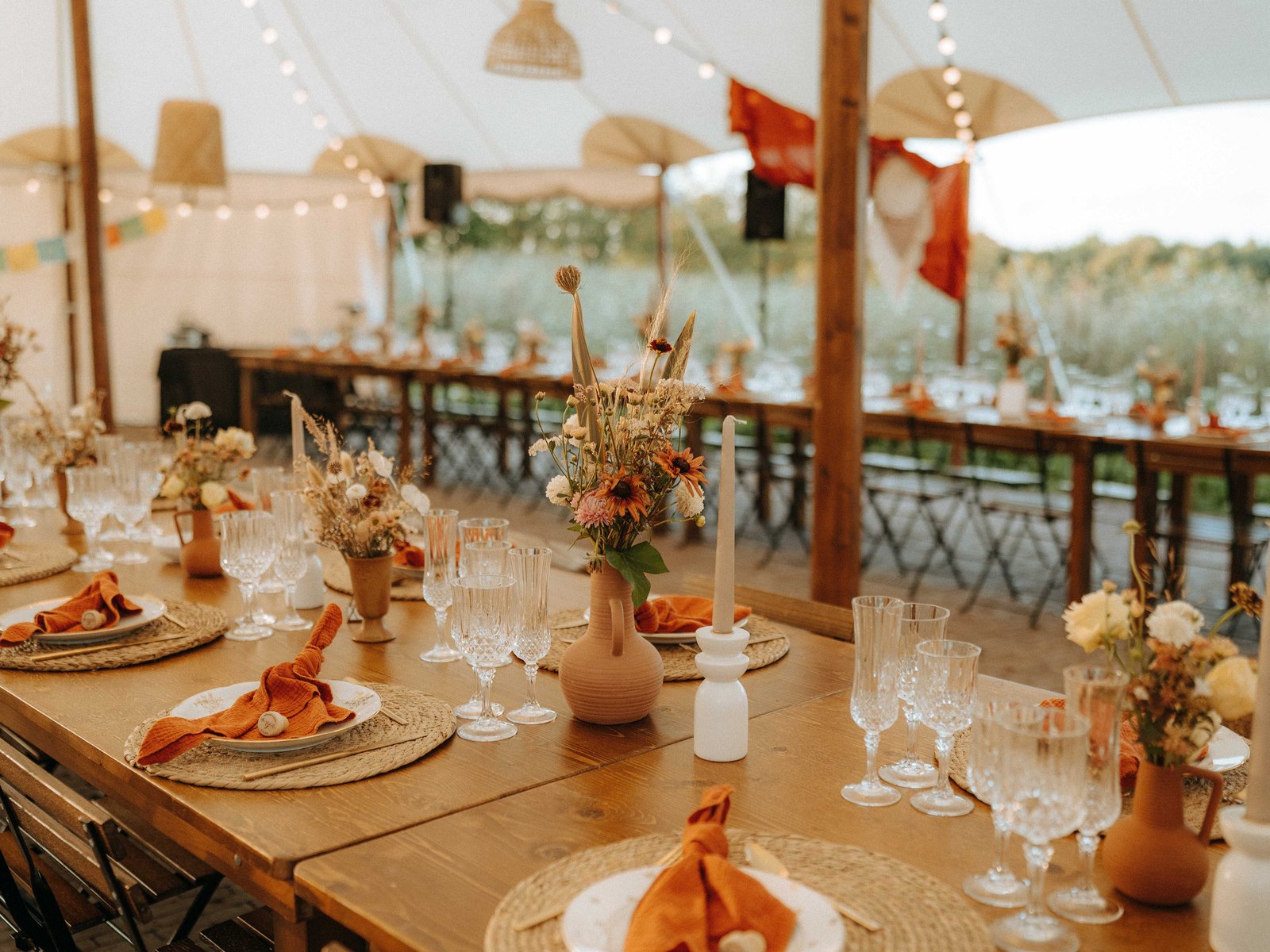 Tablée dressée aux tons terracotta sous le chapiteau